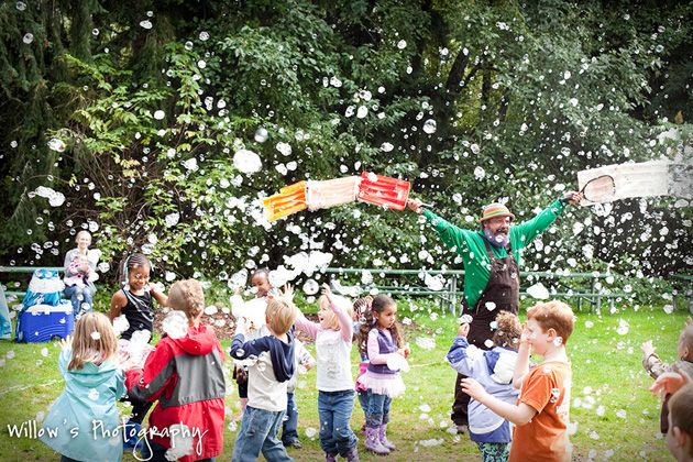 Children chasing a cloud of small bubbles in a park