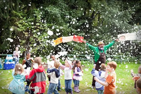 Children chasing bubbles across a park